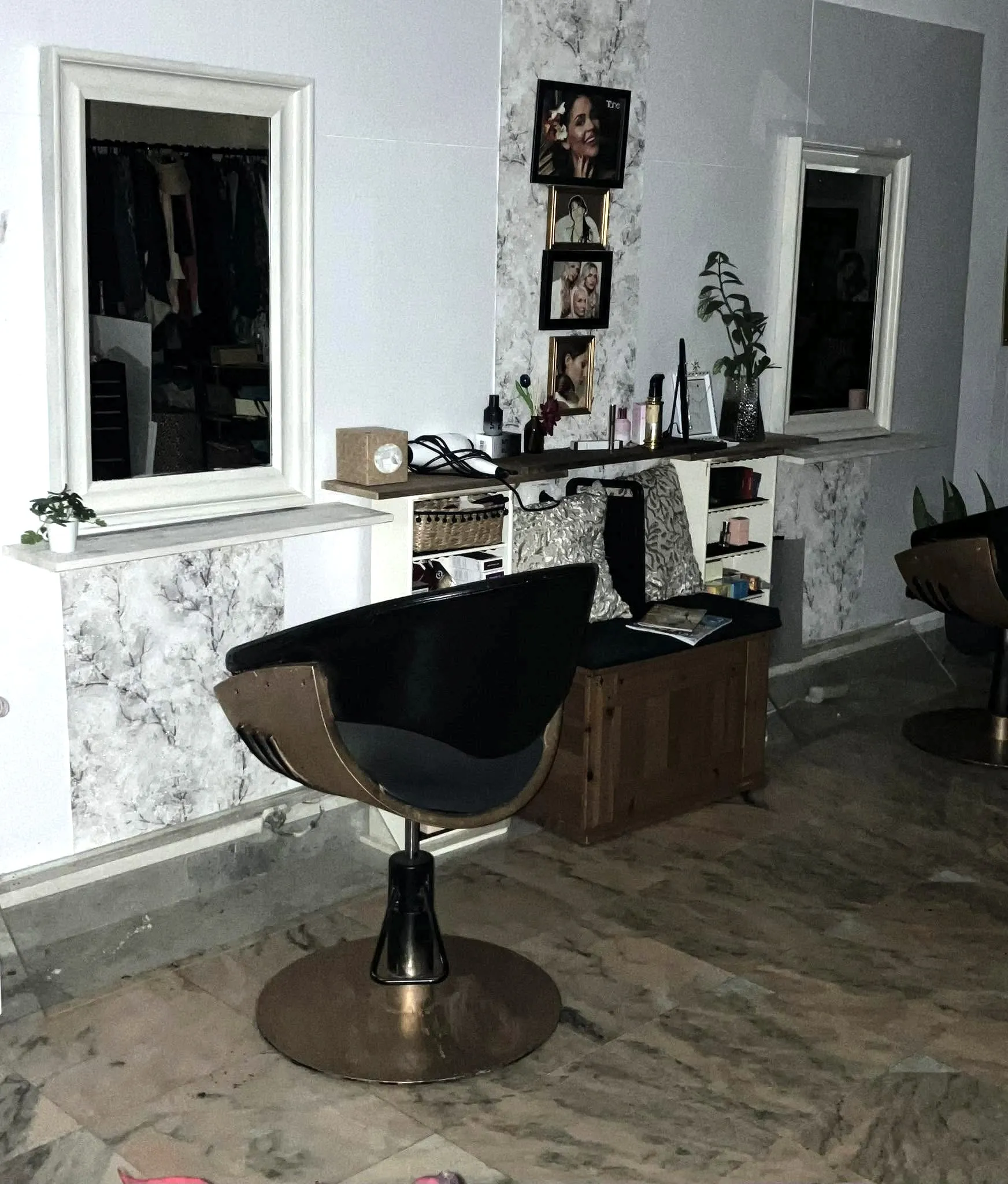 Posto de cabeleireiro com cadeira preta, espelhos e papel de parede floral