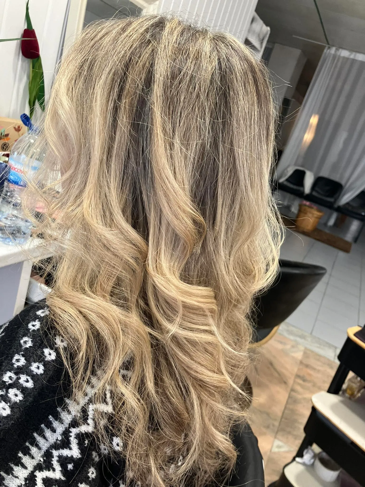Madeixas loiras com ondas suaves, vistas de costas no salão